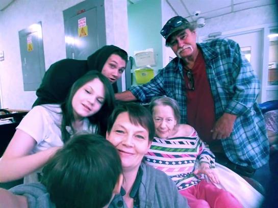 A group of family members joyfully interacts in a care facility, sharing laughter and love.