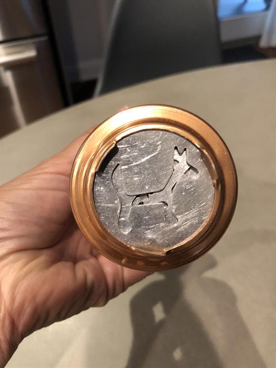 A person holds a metal object with a deer engraving, showcasing craftsmanship and design excitement.