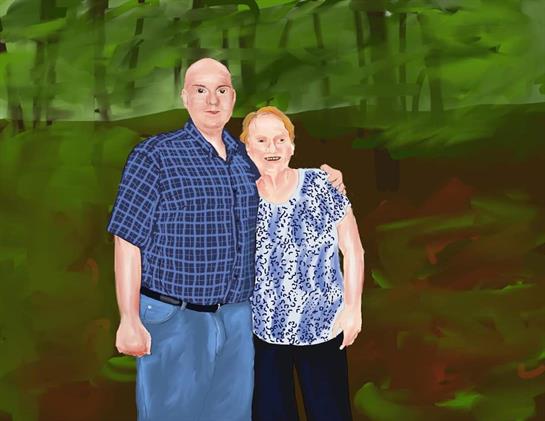 A man and a woman pose happily together surrounded by vibrant greenery.