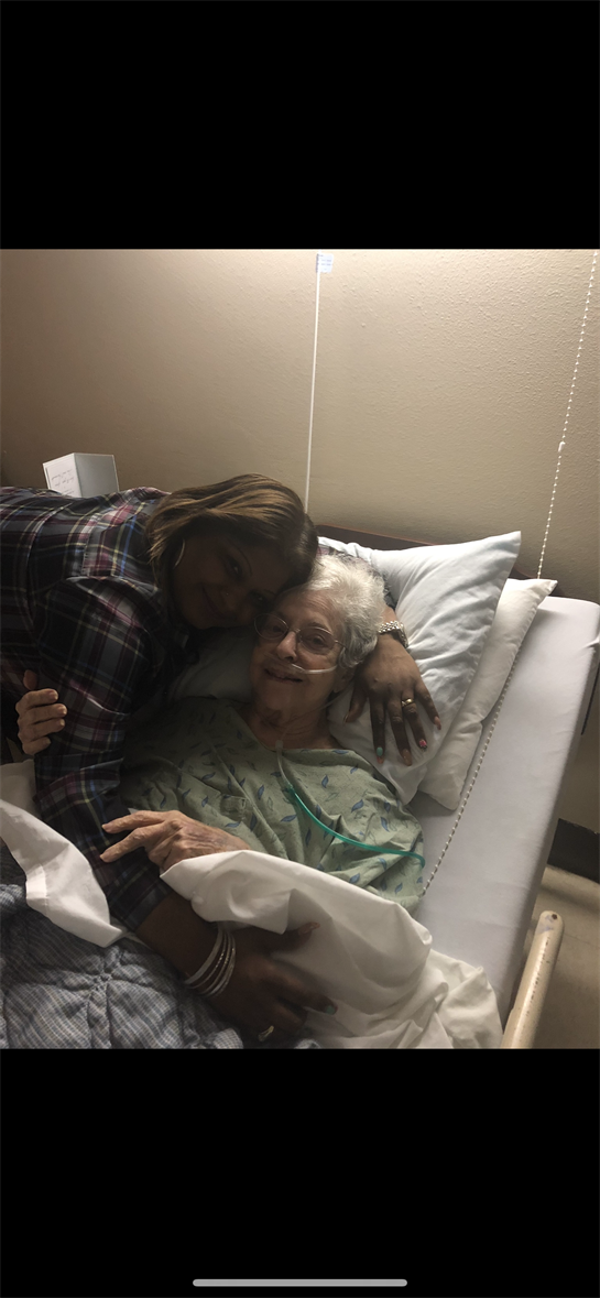 A young woman shares a heartfelt moment with her grandmother in a hospital bed.