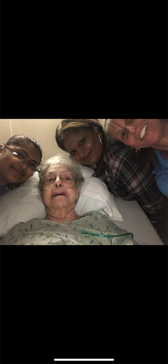 Four family members share a joyful moment with an elderly woman in her hospital room.