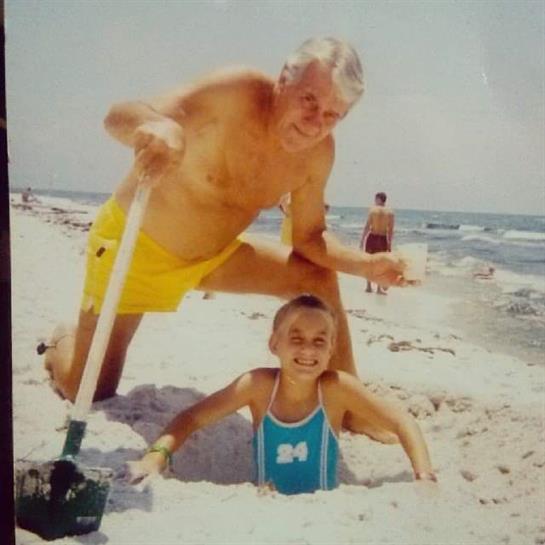 Elder man and child enjoy a summer day at the beach, digging in the sand and having fun.