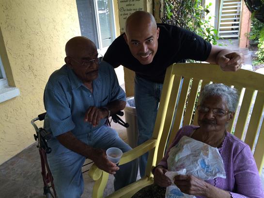 Two men enjoy a conversation with an elderly woman, promoting joyful companionship in the sun.