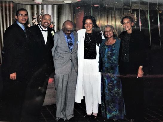 Group of family members joyfully celebrating a special moment together indoors in elegant attire.