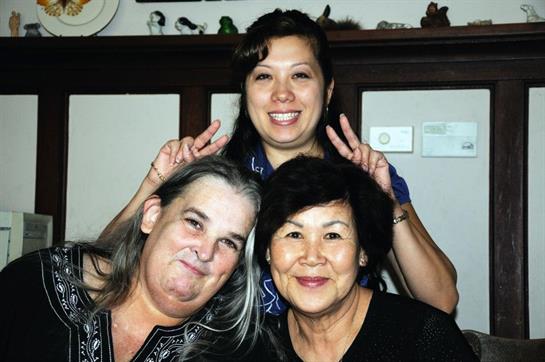 Three friends are smiling and posing together with playful expressions in a warm indoor atmosphere.
