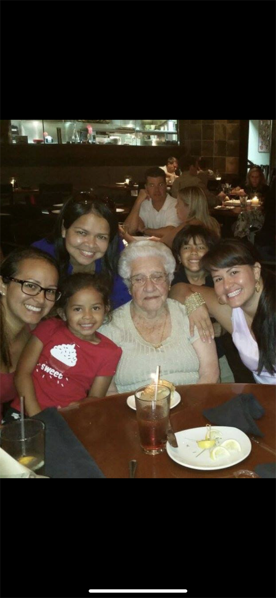 Several family members, including children and an elderly woman, celebrate together at a restaurant.