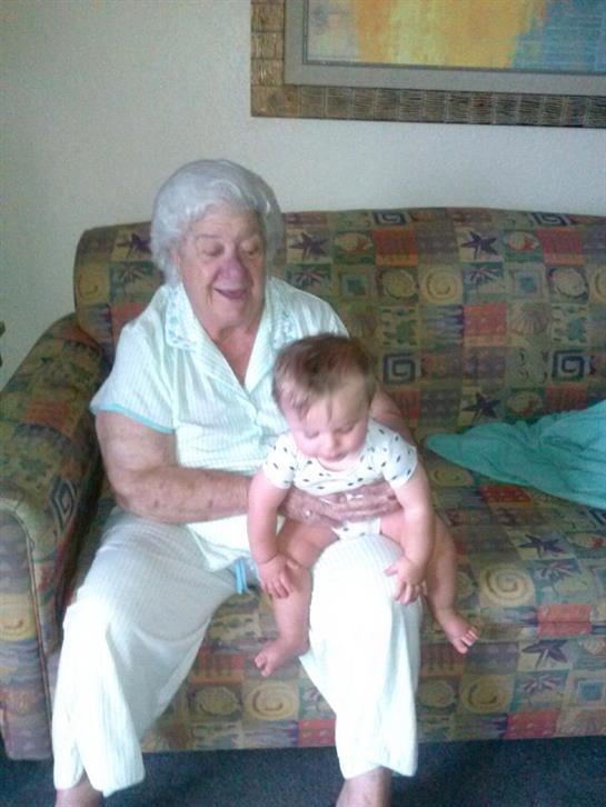 Grandmother and baby enjoy quality time together on a colorful couch in a warm living room.