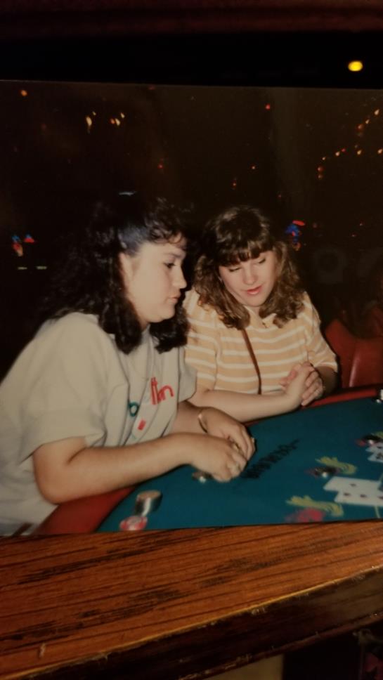Two friends share a moment while playing cards at a casino table in Las Vegas at night.