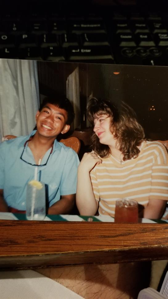 Two friends laugh together over drinks in a cozy setting.