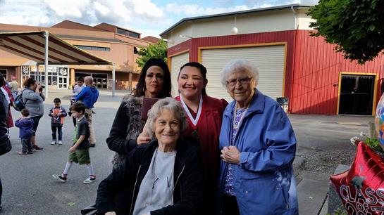 Four women happily pose at an outdoor gathering, enjoying a vibrant atmosphere together.