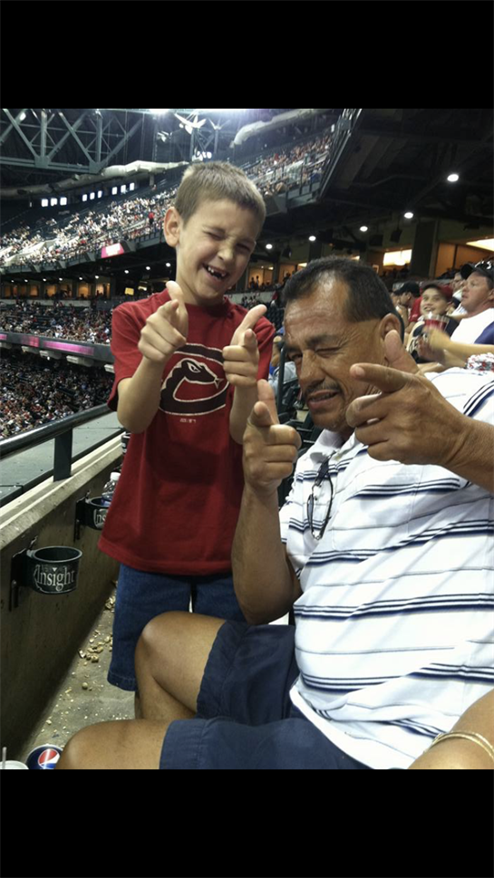 A boy and a man playfully cheer for their team at the stadium.
