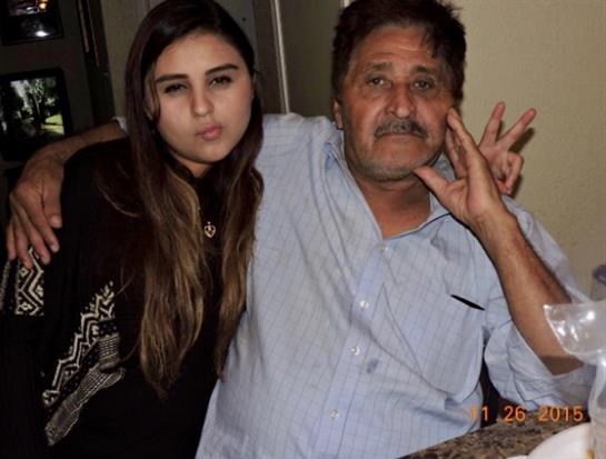 Two individuals sit closely together, smiling and engaging in a casual pose in a cozy setting.