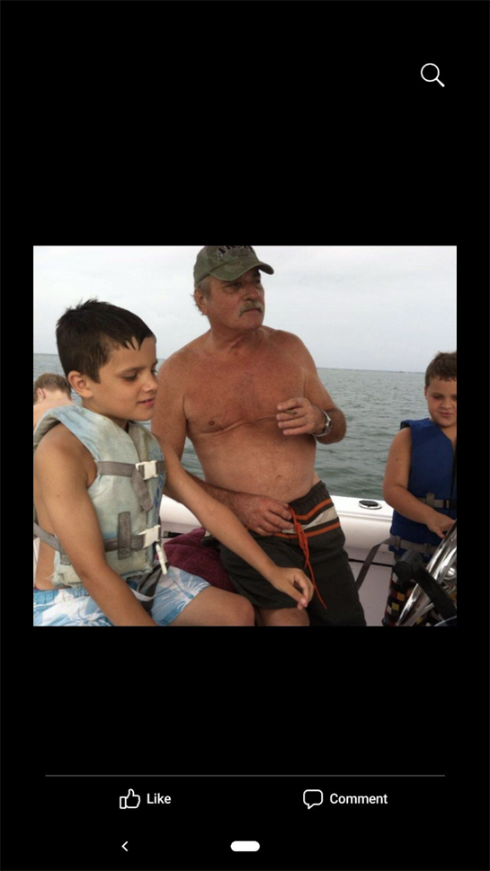 Grandfather shows his grandkids how to steer the boat while relaxing on the water.