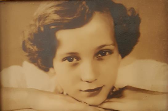 A young girl with curly hair gazes softly at the viewer, exuding an aura of innocence and grace.