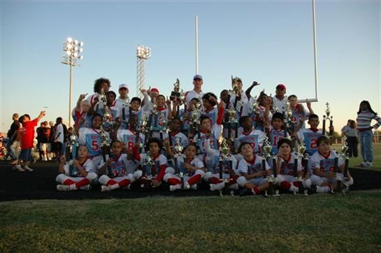 A group of young athletes proudly displays their trophies after winning a football tournament.