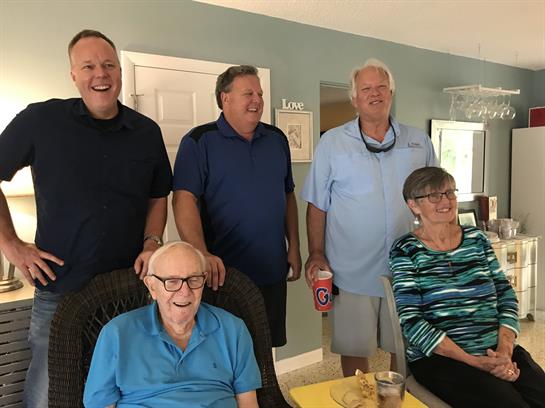Five family members are happily gathered indoors, sharing laughter and conversation.