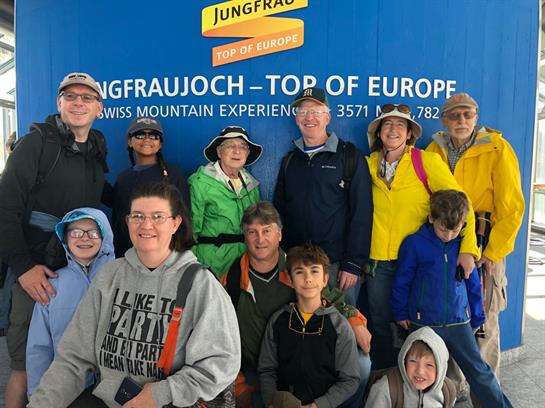 Tourists gather at Jungfraujoch, dressed for summer, smiling and enjoying their mountain adventure.