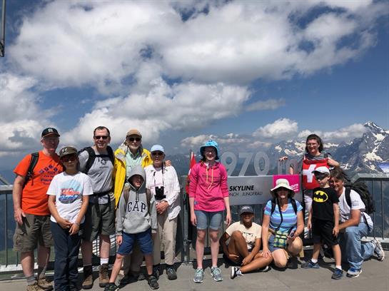 A group of hikers gathers at a mountain summit overlooking stunning cloud formations.
