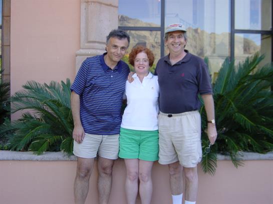 Friends share a joyful moment together by a building adorned with greenery and light.
