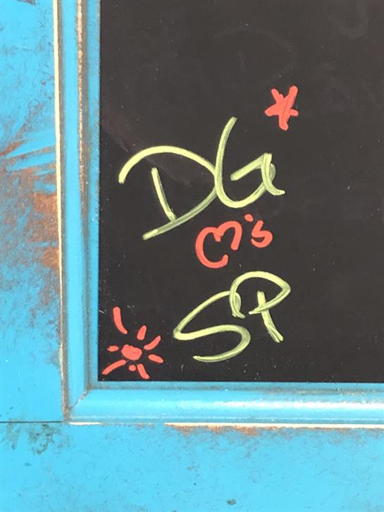 Bright chalk drawings on a turquoise frame enhance an outdoor setting, showcasing creativity.