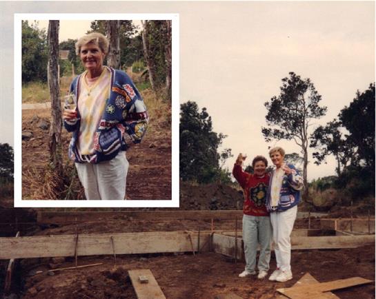 Two women celebrate at a construction site surrounded by trees, enjoying a special moment together.