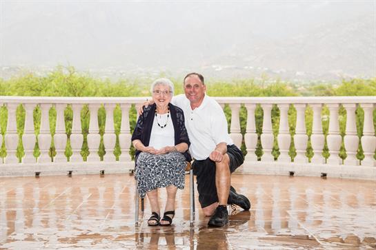 Two family members enjoy a heartfelt moment together outdoors, surrounded by lush greenery.