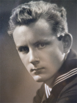 A young sailor in a navy uniform gazes intensely at the camera, capturing history.