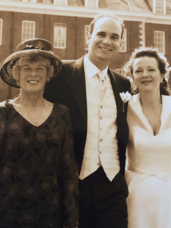 Guests celebrate a wedding day outdoors near an elegant venue, sharing joyful moments together.