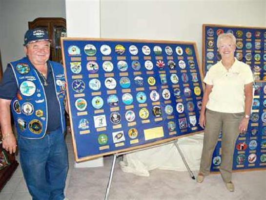 Two collectors show off their patch collection in a community hall, celebrating local heritage.
