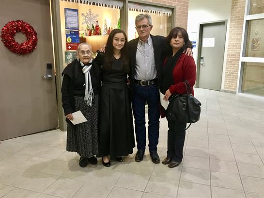 A group of four people standing together, smiling, inside a community center.