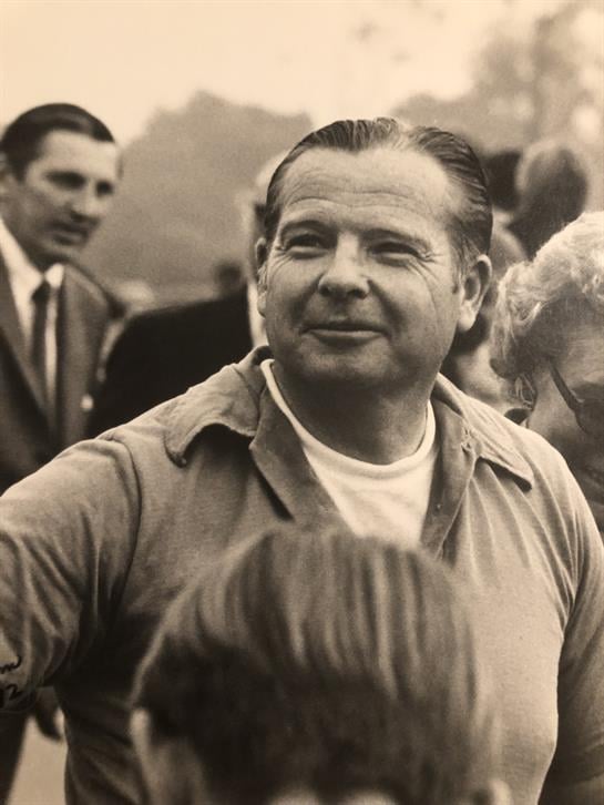 A man is engaged in conversation with attendees at a community event in a park.