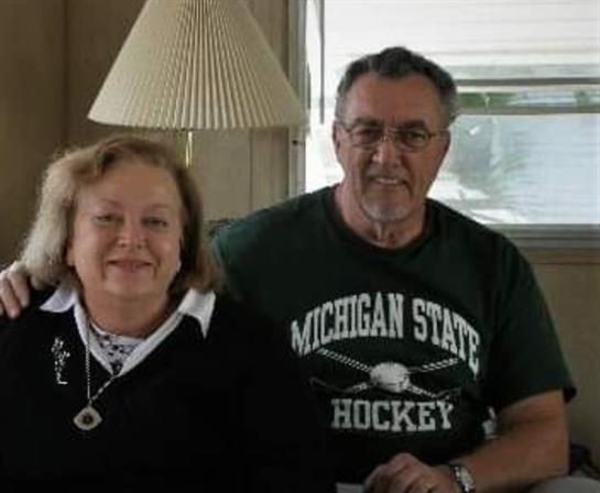 A couple smiles warmly together, surrounded by home decor and a comforting atmosphere.