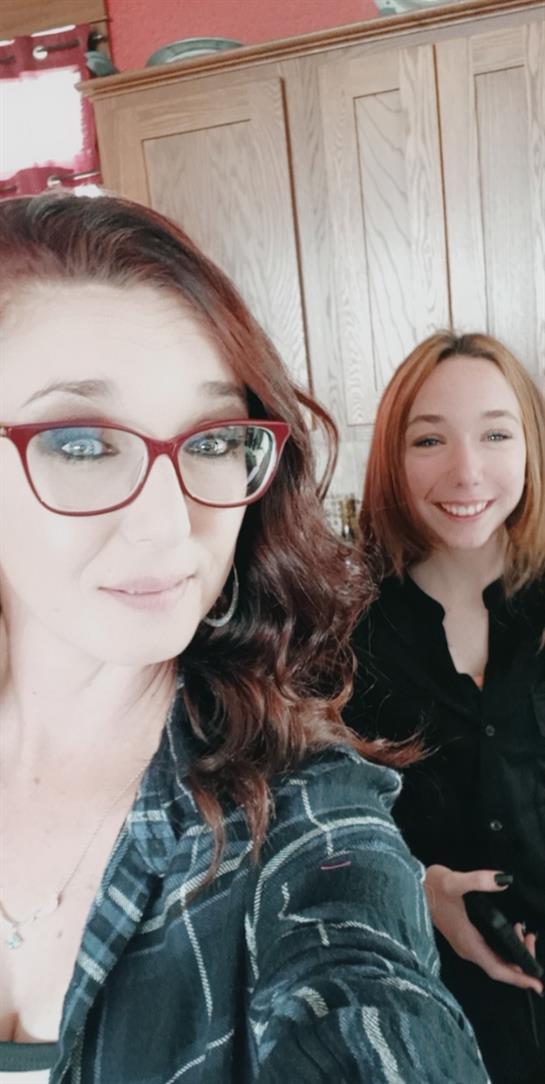 Two women share a joyful moment, smiling warmly in a cozy indoor space filled with natural light.