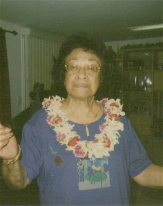 A joyful elderly woman adorned with a flower lei participates in a lively community event.