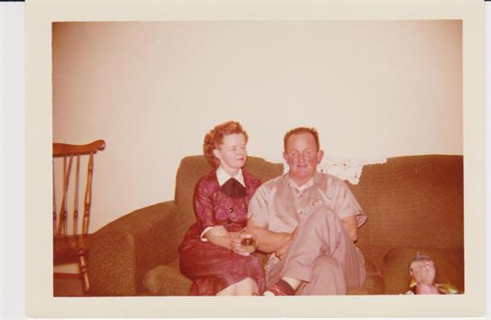 An elderly couple relaxes together on a couch in a warm and inviting living room.