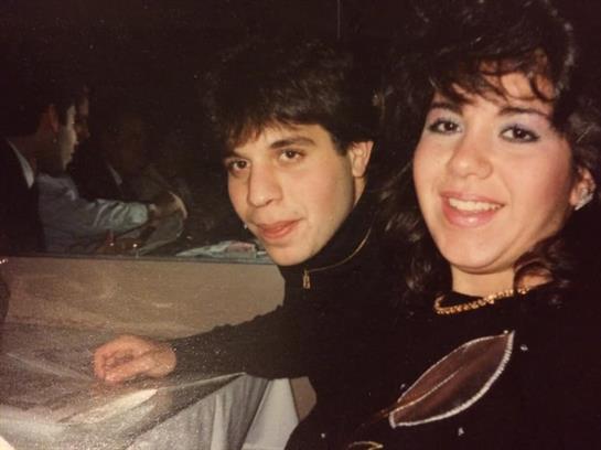 Two friends share a joyful moment at a gathering, illuminated by warm lighting and laughter.