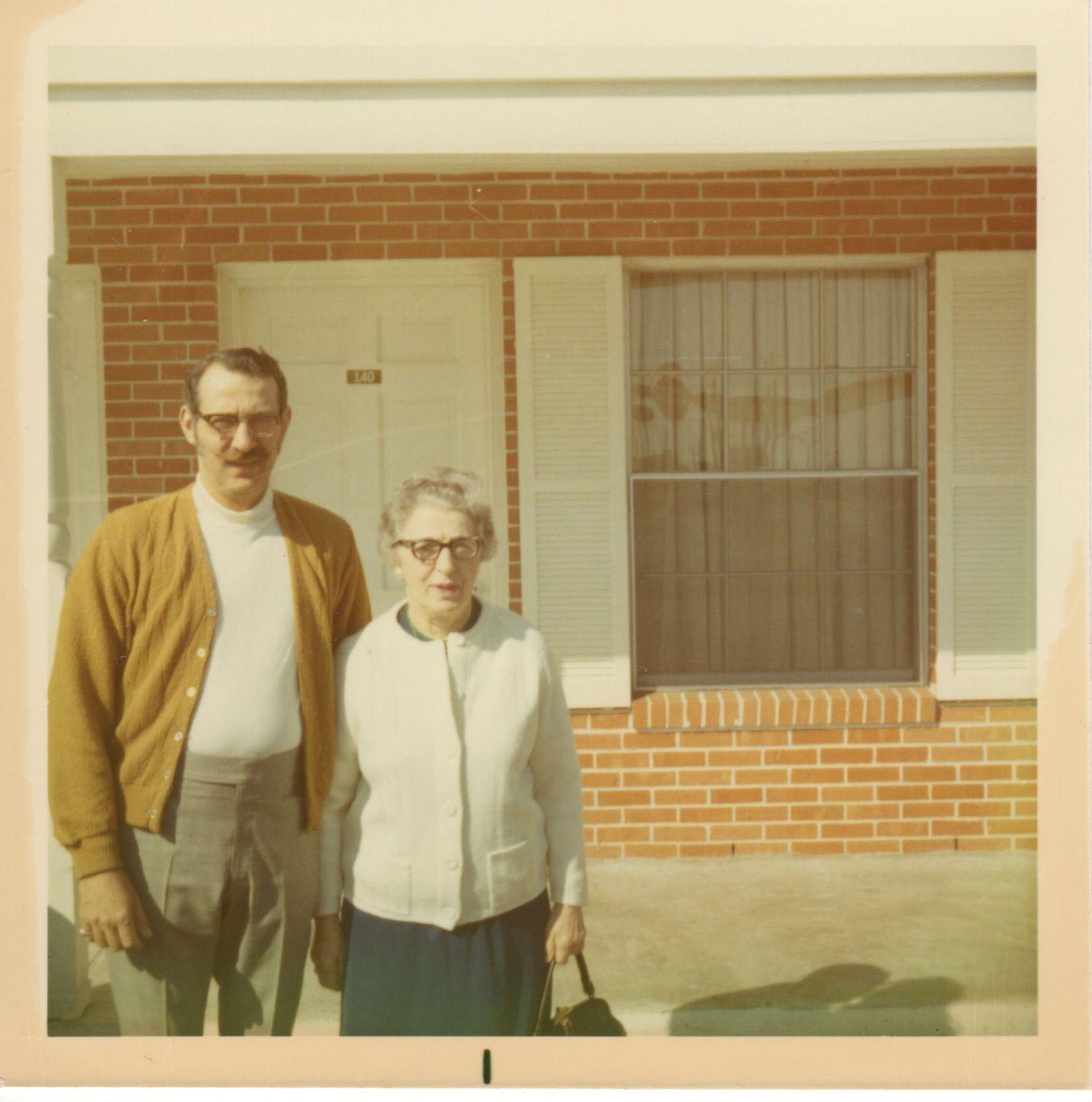 A man and woman standing in front of a brick building