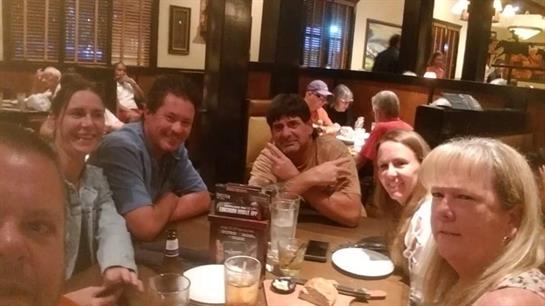 Four friends gather around a table at a busy restaurant, sharing laughter and good food.