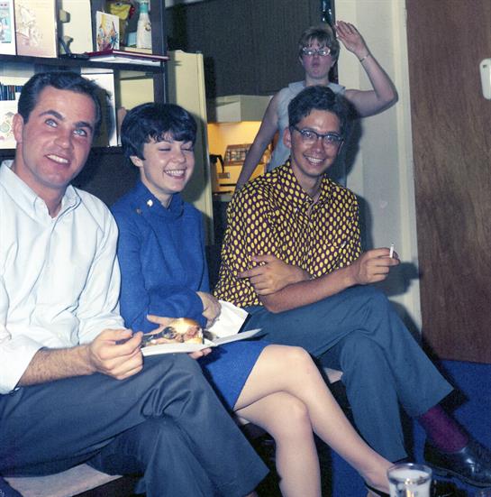 Four friends are happily engaged in conversation and enjoying dessert in a lively home setting.