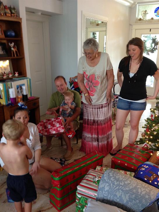 Family gathers to enjoy the festive atmosphere while opening presents together.