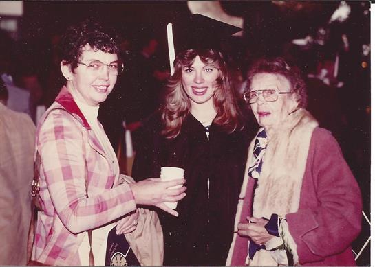 Three women are smiling and talking while holding drinks in a lively celebration.