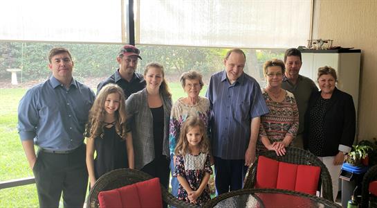 Family members pose happily indoors, smiling, and enjoying quality time together on a sunny day.