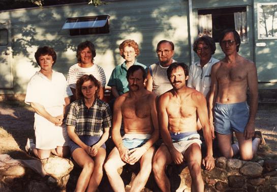 A gathering of friends poses together outdoors in summer, celebrating friendship and leisure.