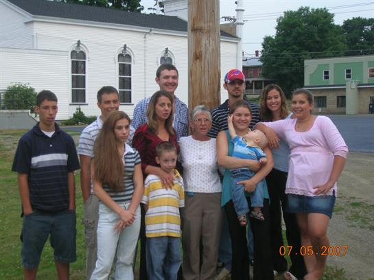 A large family poses together outdoors in front of an old church, capturing their joyful moment.