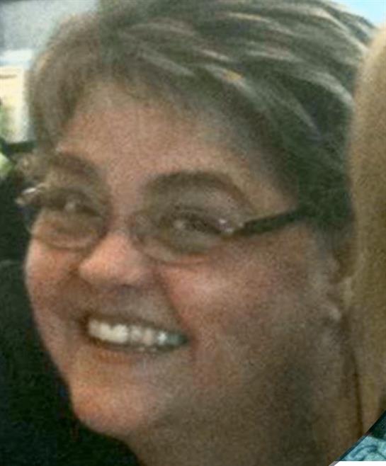 A woman is smiling happily while interacting with others at a social event in the afternoon.