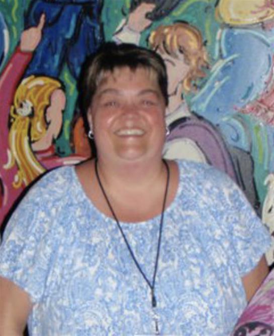 A woman stands happily in front of a vibrant mural, enjoying a community gathering.
