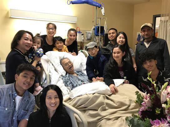 Family members support and celebrate together with an elderly man in a hospital room full of joy.