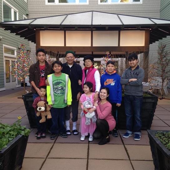 Group of family members poses together in front of a modern structure, smiling and enjoying time.