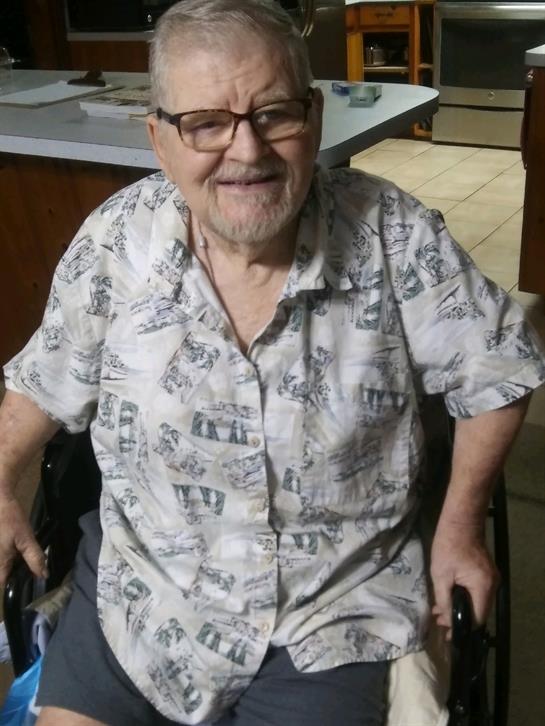 Elderly gentleman enjoys a cheerful moment in his wheelchair within a warm indoor environment.