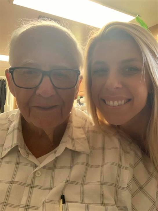 A joyful elderly man and a young woman smile together, creating a warm atmosphere in the room.